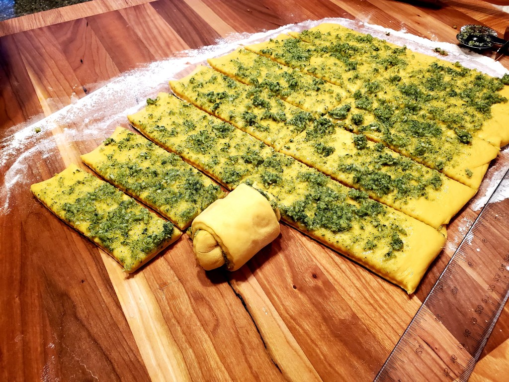 rolled out dough with pesto on top cut into strips.